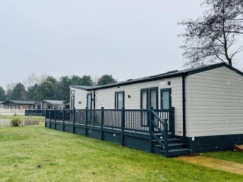 a mobile home with a porch and a fence at White Swan Lodge in Allerthorpe