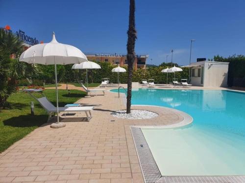 a swimming pool with chairs and umbrellas next to a pool at San Severino Park Hotel & SPA, BW Signature Collection in Mercato San Severino