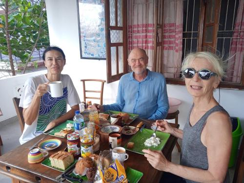 un grupo de tres personas sentadas en una mesa con comida en Blackstar Inn en Trincomalee