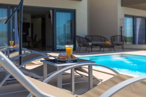 un bicchiere di succo d'arancia su un tavolo accanto alla piscina di Villa Esmeralda One by Briskva a Novigrad Istria