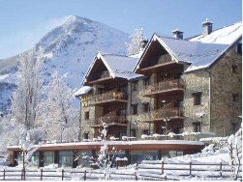 a large building in the snow with a mountain at Aparthotel Sarrato in Sallent de Gállego