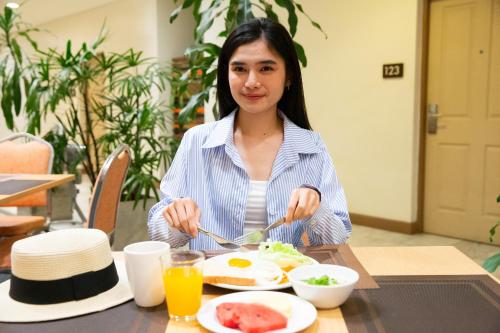 Imm Hotel Thaphae Chiang Mai في شيانغ ماي: امرأة تجلس على طاولة مع طبق من الطعام