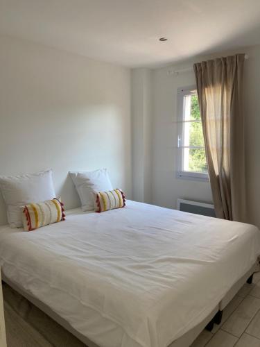 Elle comprend un grand lit blanc avec des oreillers et une fenêtre. dans l'établissement Ma Location en Provence, à Cabrières-dʼAigues