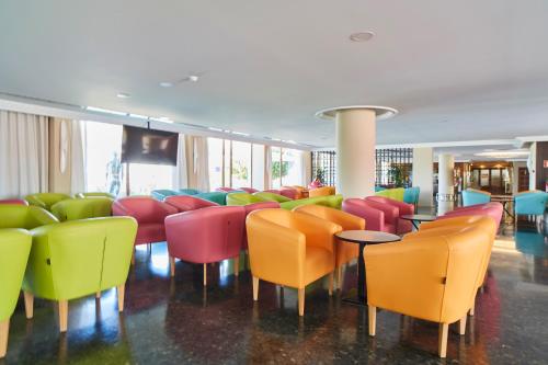 a room filled with colorful chairs and tables at Hotel Arenal in San Antonio