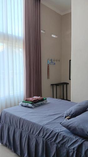 a bedroom with a blue bed with a window at Home Stay Syariah Omahku in Tlekung