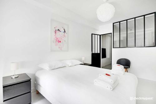 ein weißes Schlafzimmer mit einem großen Bett und einem Stuhl in der Unterkunft Amazing apartment 3BR Convention in Paris