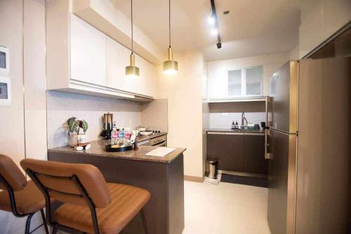 a kitchen with a counter with chairs and a refrigerator at The house of us in Manila