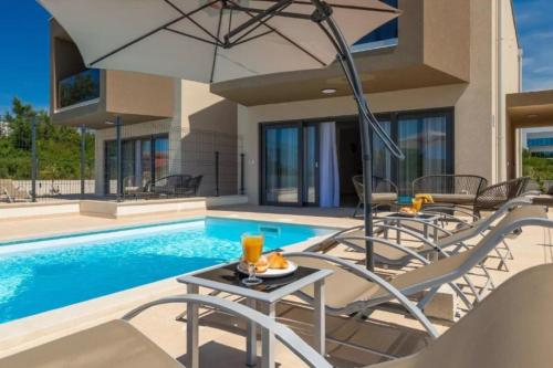 una piscina con sedie e un tavolo con ombrellone di Villa Esmeralda Two by Briskva a Novigrad Istria