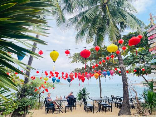 people sitting at tables on the beach with lanterns at Bãi Xếp Beach in Quy Nhon