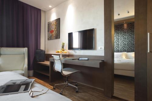a hotel room with a desk and a bed and a tv at San Paolo Hotel in Montegiorgio