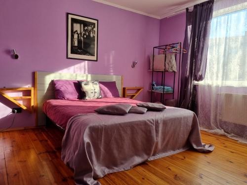 um quarto com paredes roxas e uma cama grande em ARTAPARTMENTS-center em Chernigov