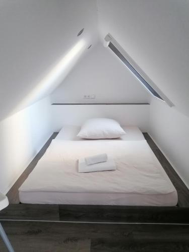 a bed in a small room with a white mattress at Ferienwohnung Mühlenblick in Großheide