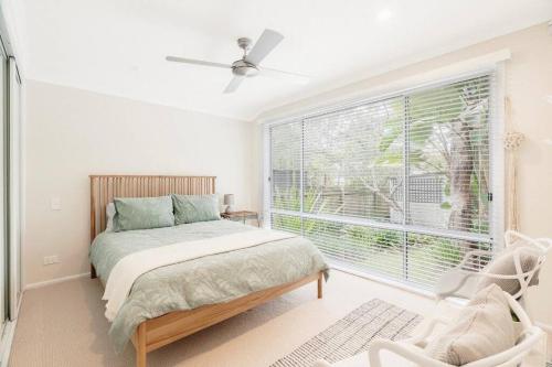 a bedroom with a bed and a large window at Loulu in Pearl Beach