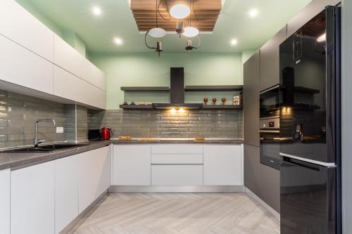 uma cozinha com armários brancos e electrodomésticos de aço inoxidável em #Amazonia Apt by halu! Apartments em Tessalônica