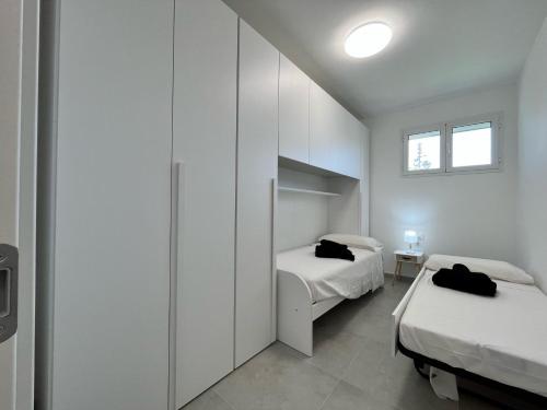 a white bedroom with two beds and a window at Marzamemi, Sul Livello del MARE, Spinazza in Marzamemi