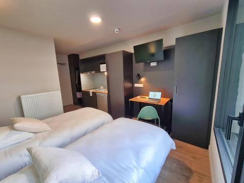 a hotel room with two beds and a desk at Montempô Appart'Hôtel Bordeaux Centre - Bassins à flot in Bordeaux