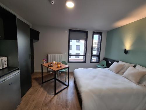a bedroom with a bed and a table in it at Montempô Appart'Hôtel Bordeaux Centre - Bassins à flot in Bordeaux