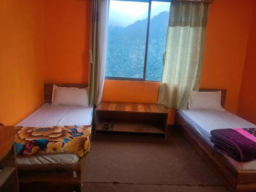 2 Betten in einem Zimmer mit Fenster in der Unterkunft Singhik Hotel Kanchen View in Singhik