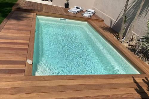 une piscine avec une terrasse en bois et une visière de piscine dans l'établissement The Chill House Grau d'Agde, au Grau-dʼAgde