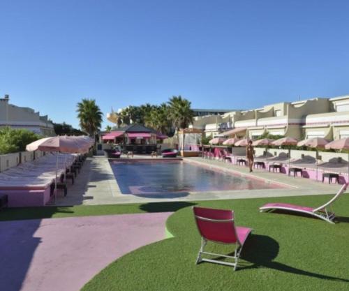 una piscina con sillas y sombrillas junto a un complejo en Village Naturiste Cap d'Agde, 208 Résidence de luxe les Jardins d'Eden "Réservée aux couples", en Cap d'Agde