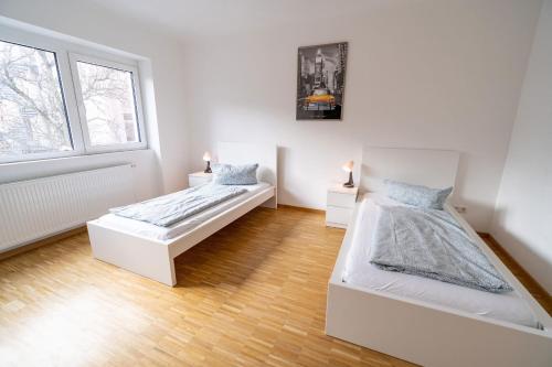 2 camas en una habitación blanca con ventana en ATRIUM - moderne, großzügige Wohnung 1OG MARIE en Ludwigshafen am Rhein
