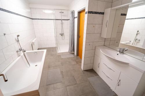 Baño blanco con bañera y lavamanos en ATRIUM - komfortables Apartment HORCHHEIMER en Worms