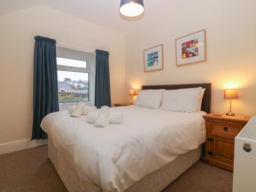 a bedroom with a large white bed with a window at Castell in Pwllheli