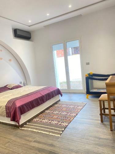 a bedroom with a bed and a table and a rug at Dar Lili Djerba in Mezraya