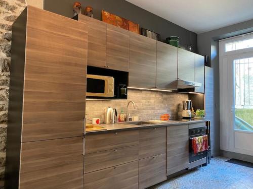 - une cuisine avec des placards en bois et un four micro-ondes dans l'établissement Appartement à 30m de la plage du Sillon., à Saint-Malo