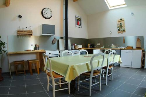 une cuisine avec une table et des chaises et une horloge au mur dans l'établissement Le Jardin de l'Albert, à Beurey-Bauguay