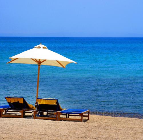 two chairs and an umbrella on a beach at Retac Qunay Dahab Resort & SPA in Dahab