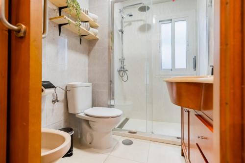 a bathroom with a toilet and a shower and a sink at San Pagés 3BR Apartment in Seville