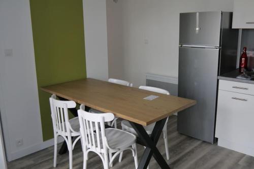 - une cuisine avec une table en bois et des chaises blanches dans l'établissement Villa la garenne : Chausey, à La Bernerie-en-Retz