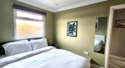 sypialnia z białym łóżkiem i oknem w obiekcie Victoria House by Switchback Stays w Cardiff
