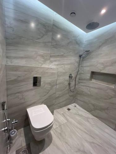 a bathroom with a white toilet and a shower at Serene roof A quiet romantic luxurious in Kuwait