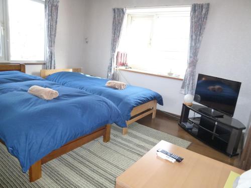 a room with three beds and a television and a table at Otaru - House / Vacation STAY 57190 in Otaru