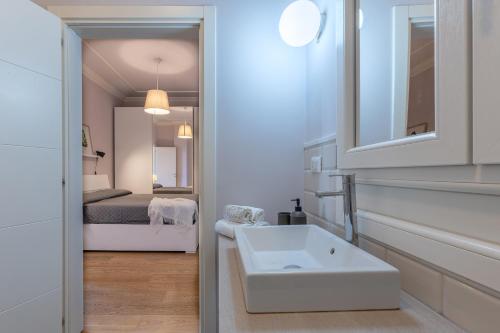 ein weißes Badezimmer mit einem Waschbecken und ein Schlafzimmer in der Unterkunft Bolo Stay Central Apartment in Bologna