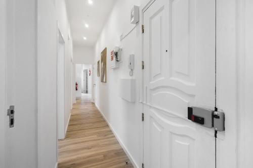 un corridoio con pareti bianche e pavimenti in legno di Smart Living Hub: Designer Spaces for Digital Nomads & Remote Workers a Lisbona