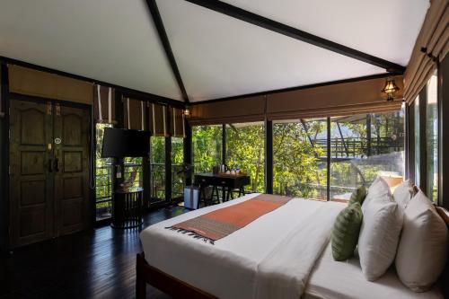 a bedroom with a large bed with a large window at Kachonghills Tented Resort Trang in Trang