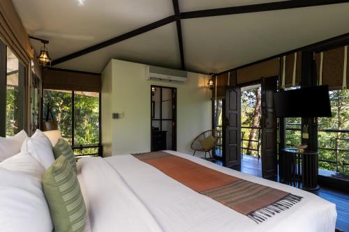 a bedroom with a large white bed and windows at Kachonghills Tented Resort Trang in Trang