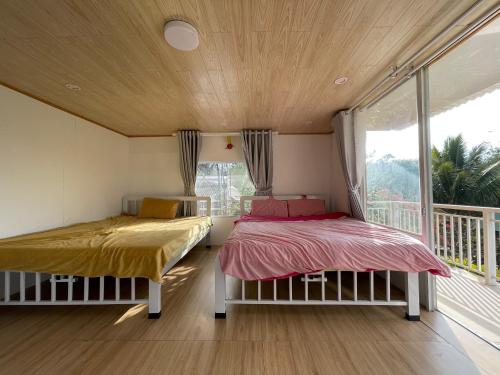 two beds in a room with a window at Chú Ba Farmstay - cách Đà Lạt 40km in Ấp Phú Thuận