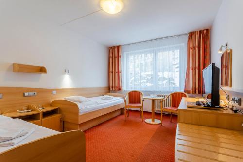 um quarto de hotel com duas camas e uma televisão em Complex Curie em Jáchymov