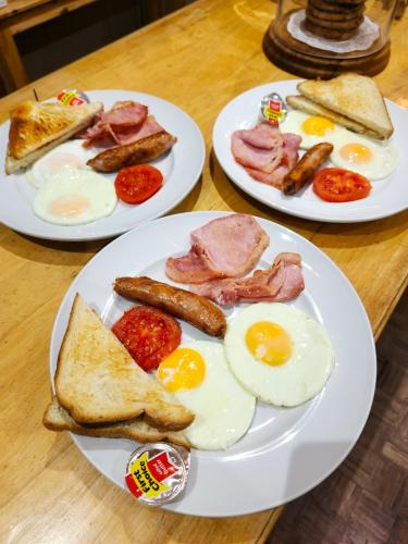 three plates of breakfast food on a wooden table at Mijn Kitchen Coffee Shop and B&B in Blantyre