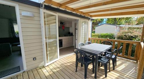 un patio avec une table et des chaises sur une terrasse dans l'établissement Mobile home n°261 2chambres à 2 pas du lac !, à Gastes