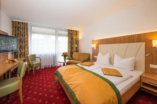 a hotel room with a large bed and a desk at Johannesbad Thermalhotel Ludwig Thoma in Bad Füssing