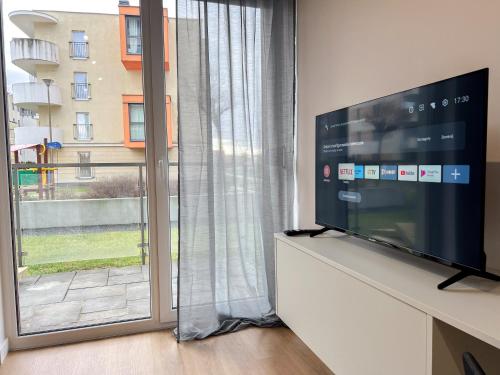 salon z telewizorem i dużym oknem w obiekcie Hann Harmony Apartments Koszyka 45 w mieście Opole