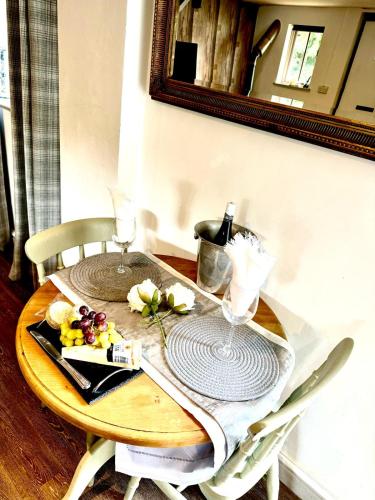 a table with a mirror and a table with flowers on it at Stable boys cottage in Sedgeberrow