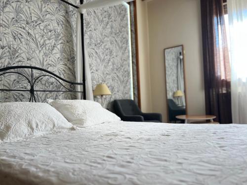 1 dormitorio con 1 cama blanca y 1 silla en Hotel Rural Restaurante Las Baronas, en Santa Cruz de la Salceda