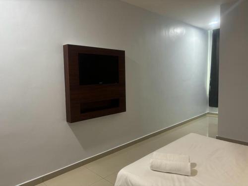 a room with a tv on a white wall at Codidik Hotel in Kuantan