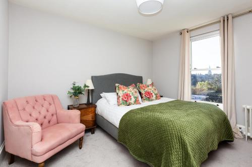 a bedroom with a bed and a pink chair at Lewknor Lodge: Stunning 5 bed, 4 bathroom house in Ramsgate in Kent